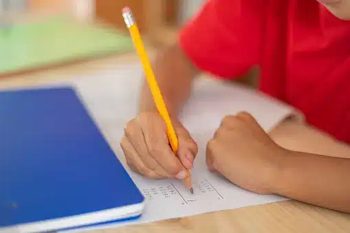 Close-Up Of A Primary School Child's Hand Doing Math Homework. Back To School.