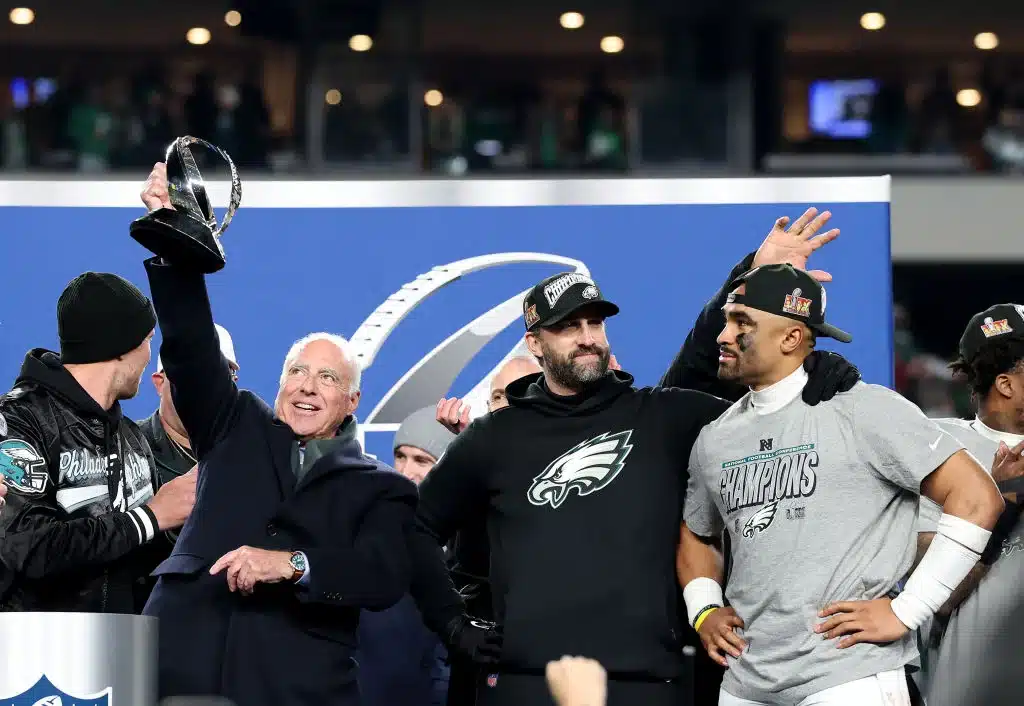 Owner Jeffrey Lurie celebrates with the George Halas trophy alongside head coach Nick Sirianni and Jalen Hurts #1 of the Philadelphia Eagles