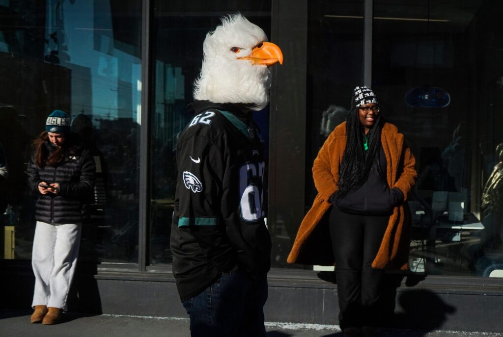 Philadelphia Eagles fans and a man in an Eagle head gather along South Broad Street ahead of the Eagles’ Super Bowl 59 victory parade